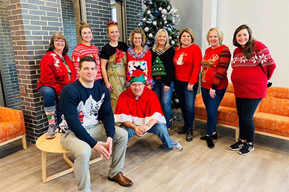 Culture and Careers - Team in Holiday Sweaters in Front of a Christmas Tree Larger